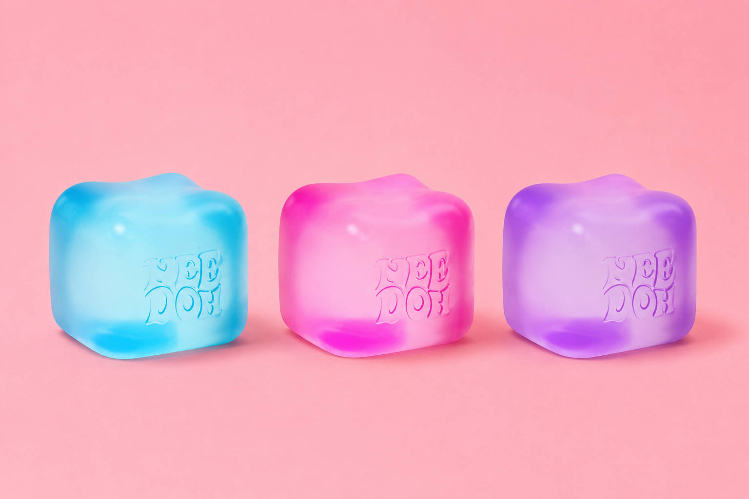 Pastel NeeDoh squishy cubes in blue pink and purple on pink background